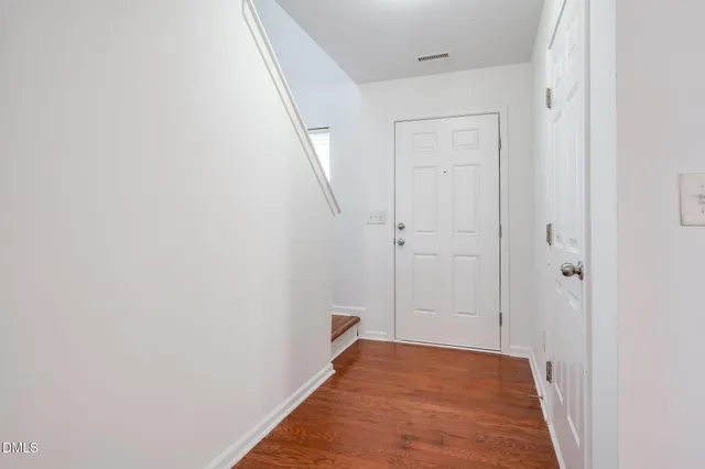 a view of an empty room with wooden floor and windows