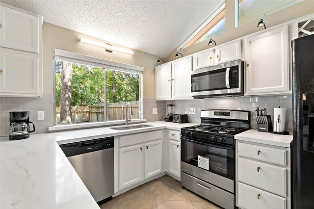 a kitchen with white cabinets appliances and window