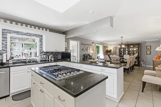 a kitchen with a stove a sink dishwasher and white cabinets with wooden floor