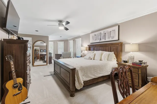 a spacious bedroom with a bed a flat tv screen and dresser