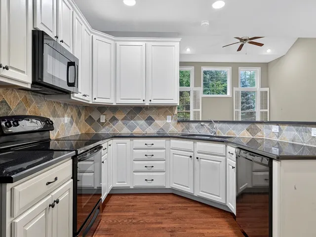 a kitchen with granite countertop white cabinets and white appliances