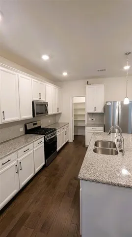 a large kitchen with kitchen island a stove a sink dishwasher and a dining table with wooden floor