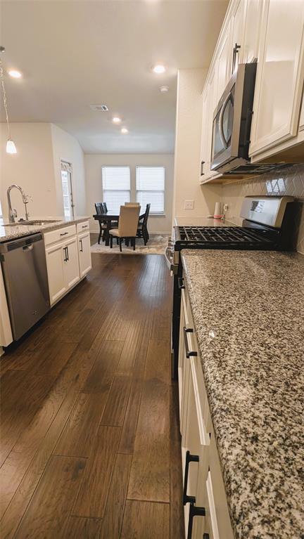 2408 Wildhaven Road Crandall, TX 75114 - Photo 18 of 39 Kitchen featuring light stone countertops, white cabinetry, dark wood-style floors, appliances with stainless steel finishes, and decorative light fixtures