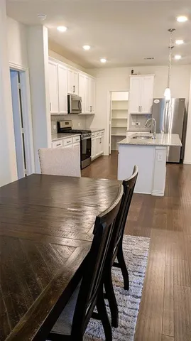 a kitchen with stainless steel appliances a dining table chairs microwave and sink