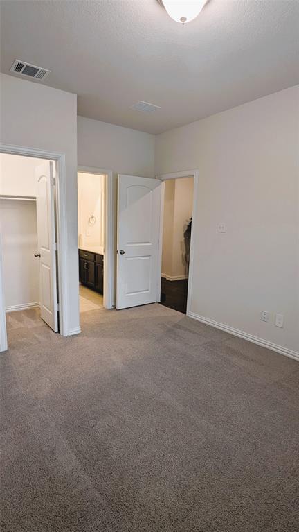 2408 Wildhaven Road Crandall, TX 75114 - Photo 4 of 39 Unfurnished bedroom featuring a walk in closet, light colored carpet, a textured ceiling, and ensuite bath