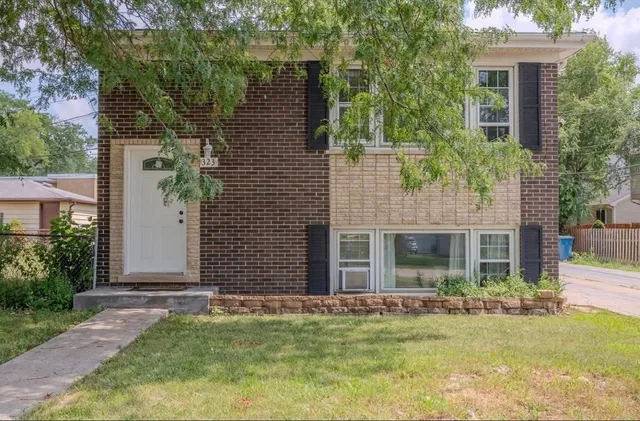 a view of a house with brick walls and a yard with plants
