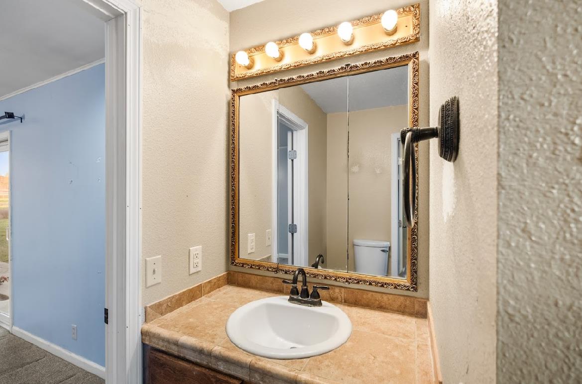 3402 Burson Road Burson, CA 95225 - Photo 33 of 65 a bathroom with a granite countertop sink and a mirror