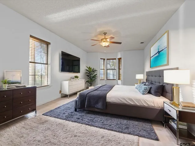 a bedroom with a bed couches chair and a flat tv screen