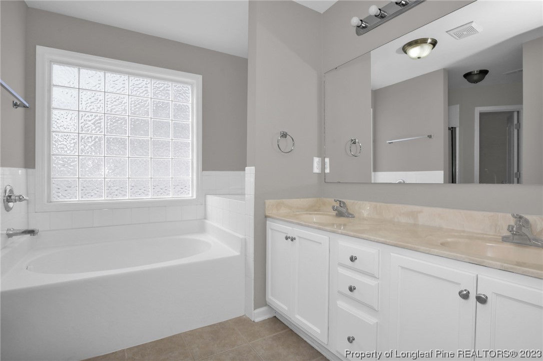 92 Holly Oak Circle Bunnlevel, NC 28323 - Photo 13 of 23 a bathroom with a granite countertop tub a sink and a window
