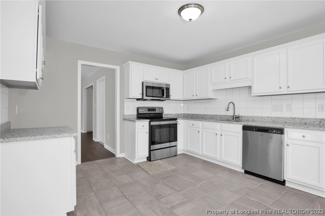 92 Holly Oak Circle Bunnlevel, NC 28323 - Photo 9 of 23 a kitchen with granite countertop white cabinets and stainless steel appliances