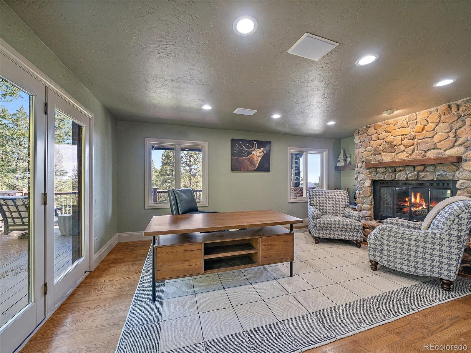 33442 Meadow Mountain Road Evergreen, CO 80439 - Photo 20 of 40 a living room with furniture a large window and a fireplace