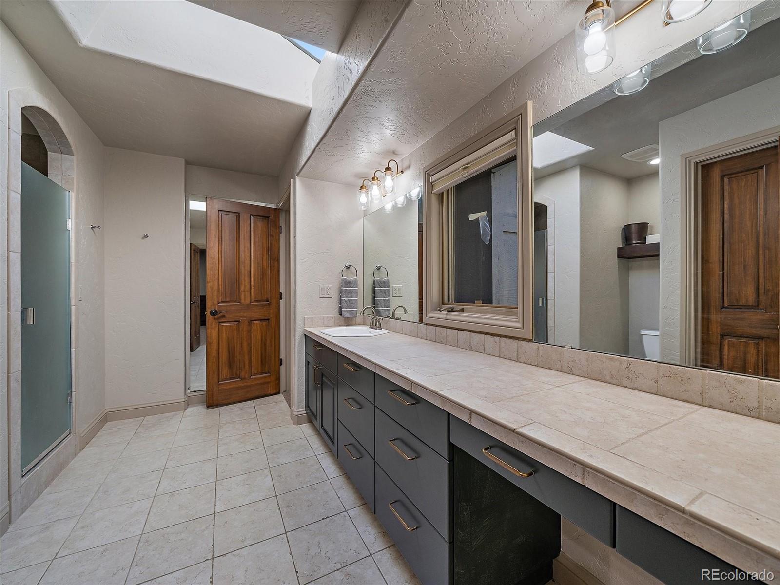33442 Meadow Mountain Road Evergreen, CO 80439 - Photo 26 of 40 a large bathroom with a large mirror vanity and shower