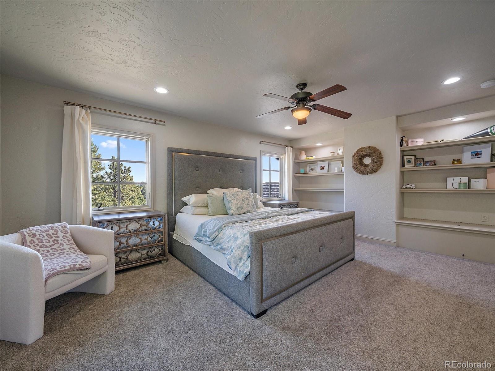 33442 Meadow Mountain Road Evergreen, CO 80439 - Photo 28 of 40 a spacious bedroom with a bed and ceiling fan