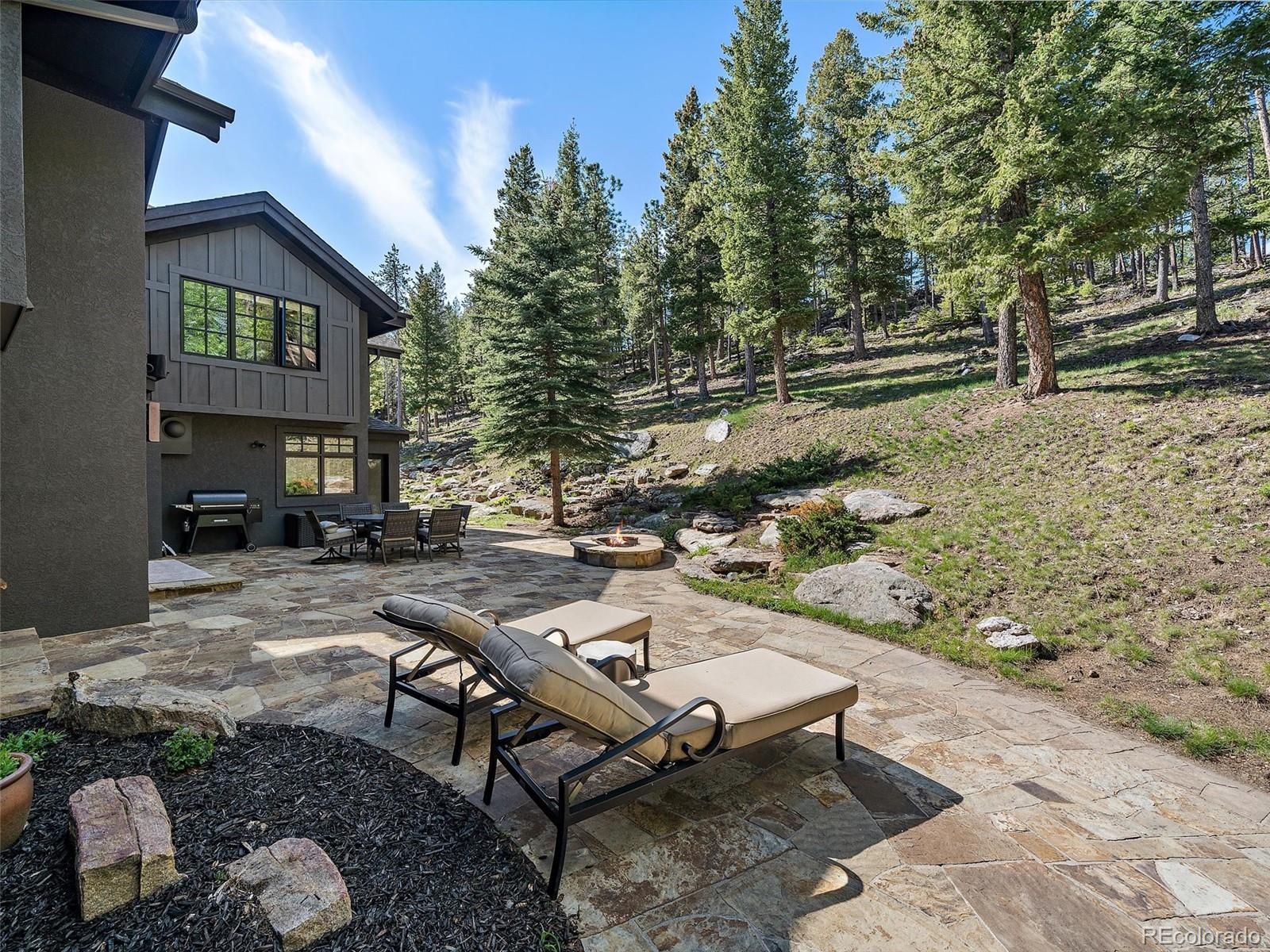 33442 Meadow Mountain Road Evergreen, CO 80439 - Photo 36 of 40 a view of a patio with table and chairs with wooden fence and plants