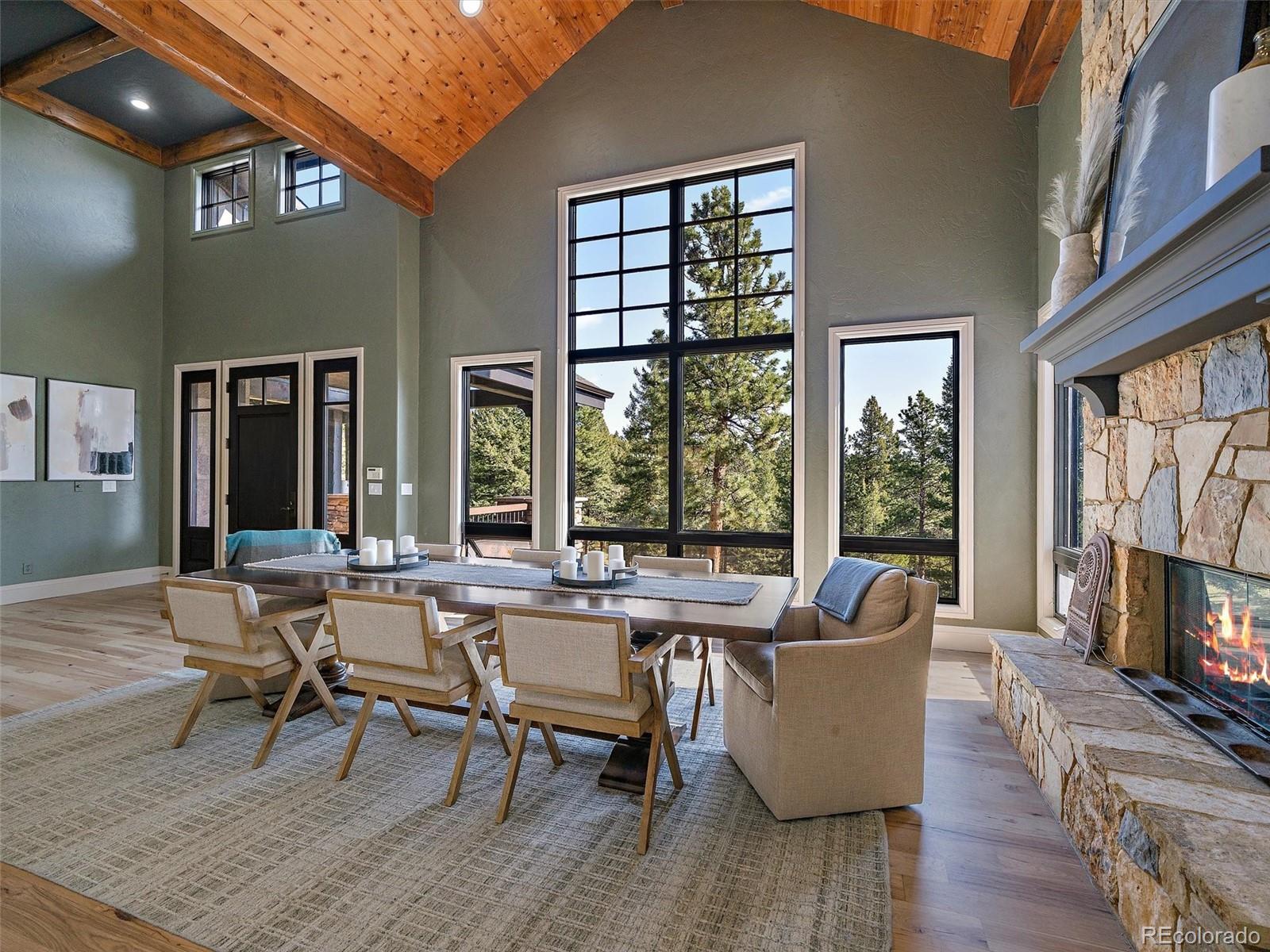 33442 Meadow Mountain Road Evergreen, CO 80439 - Photo 6 of 40 a view of a livingroom and dining room with wooden floor and a fireplace