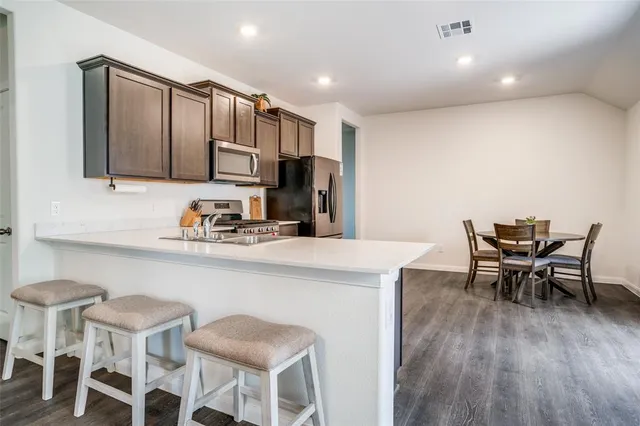 a kitchen with a dining table chairs and wooden floor