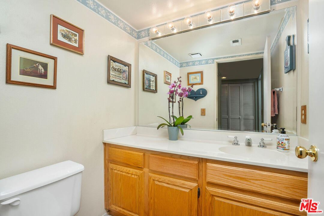 22211 Frontier Place Chatsworth, CA 91311 - Photo 9 of 26 a bathroom with a granite countertop sink mirror vanity and toilet