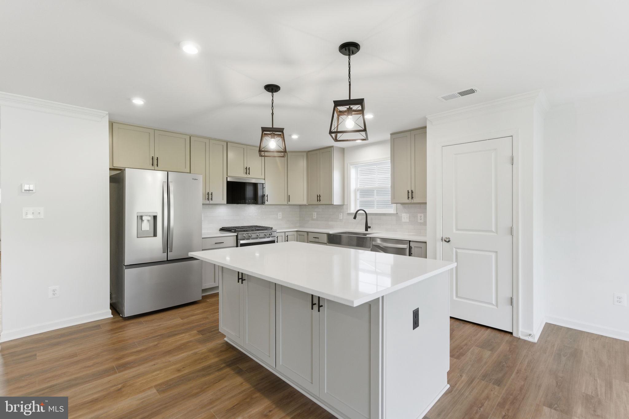 a kitchen with stainless steel appliances granite countertop a sink a stove a refrigerator and island with wooden floor