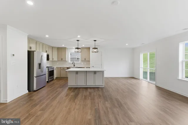 a large kitchen with a center island wooden floor stainless steel appliances and windows