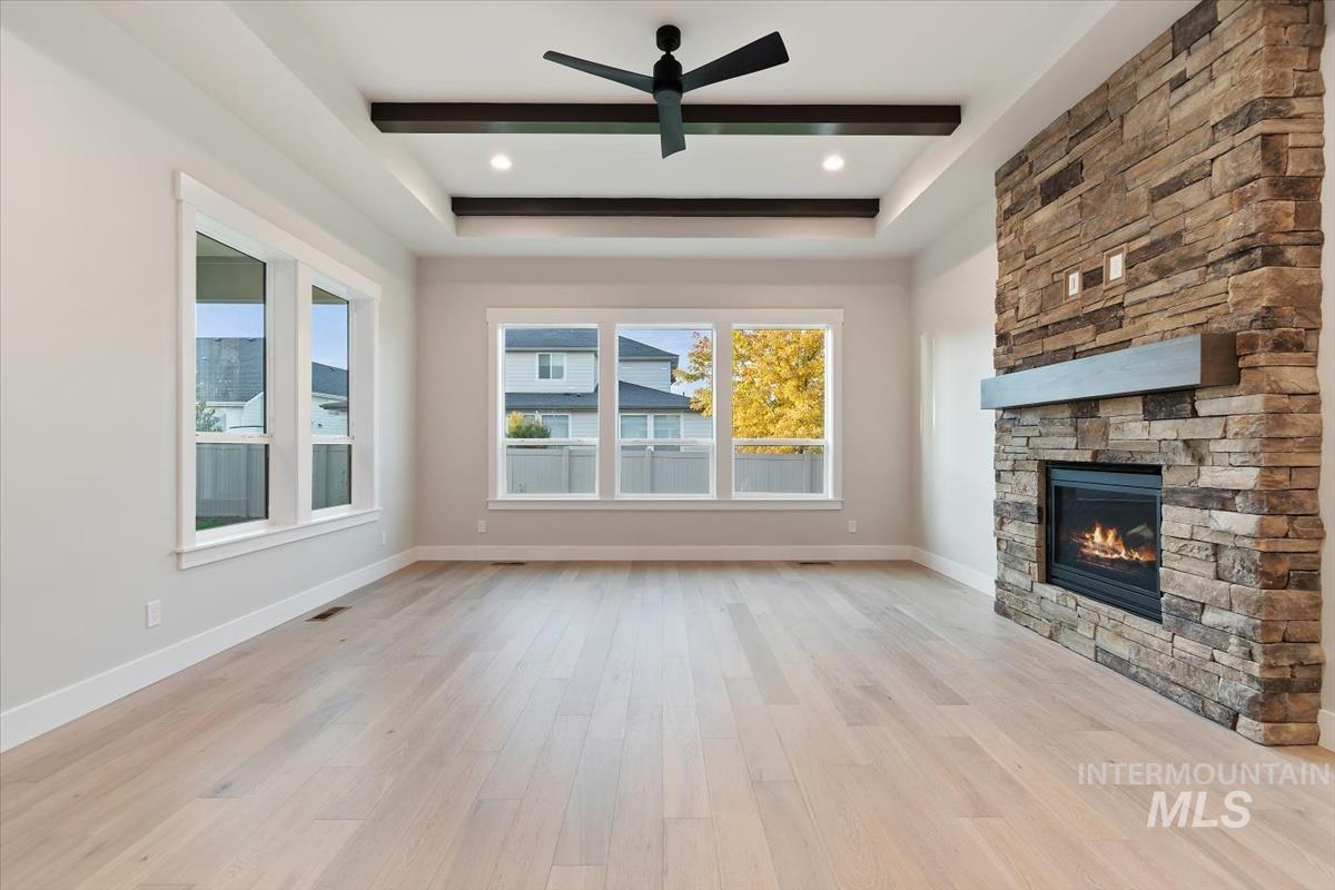2147 East Blakehurst Avenue Kuna, ID 83634 - Photo 5 of 43 Unfurnished living room featuring a raised ceiling, light wood-type flooring, a stone fireplace, and recessed lighting