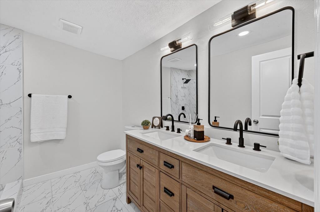 538 Pemberton Hill Road Dallas, TX 75217 - Photo 19 of 31 Dual vanity with wood-finish cabinetry, white countertops, and matte black fixtures