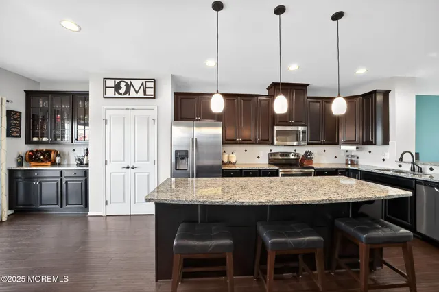 a kitchen with stainless steel appliances granite countertop a kitchen island a stove a sink a dining table and chairs