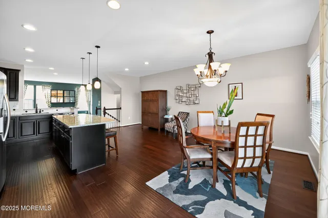 a dining room with wooden floor a chandelier a wooden table and chairs