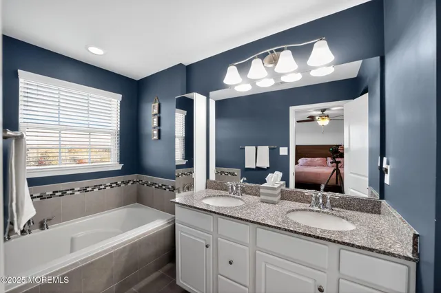 a bathroom with a tub a double vanity sink and a large mirror