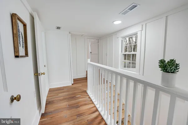 a view of a hallway with wooden floor and stairs