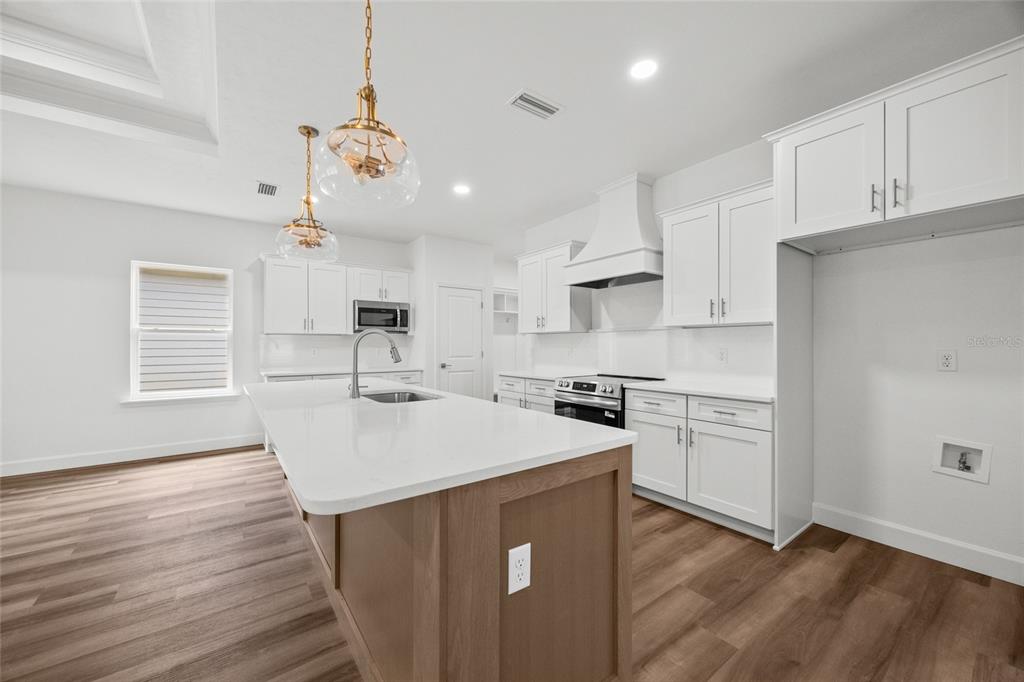 1099 Southwest 66th Terrace Gainesville, FL 32607 - Photo 24 of 35 a kitchen with a sink a stove a refrigerator and white cabinets