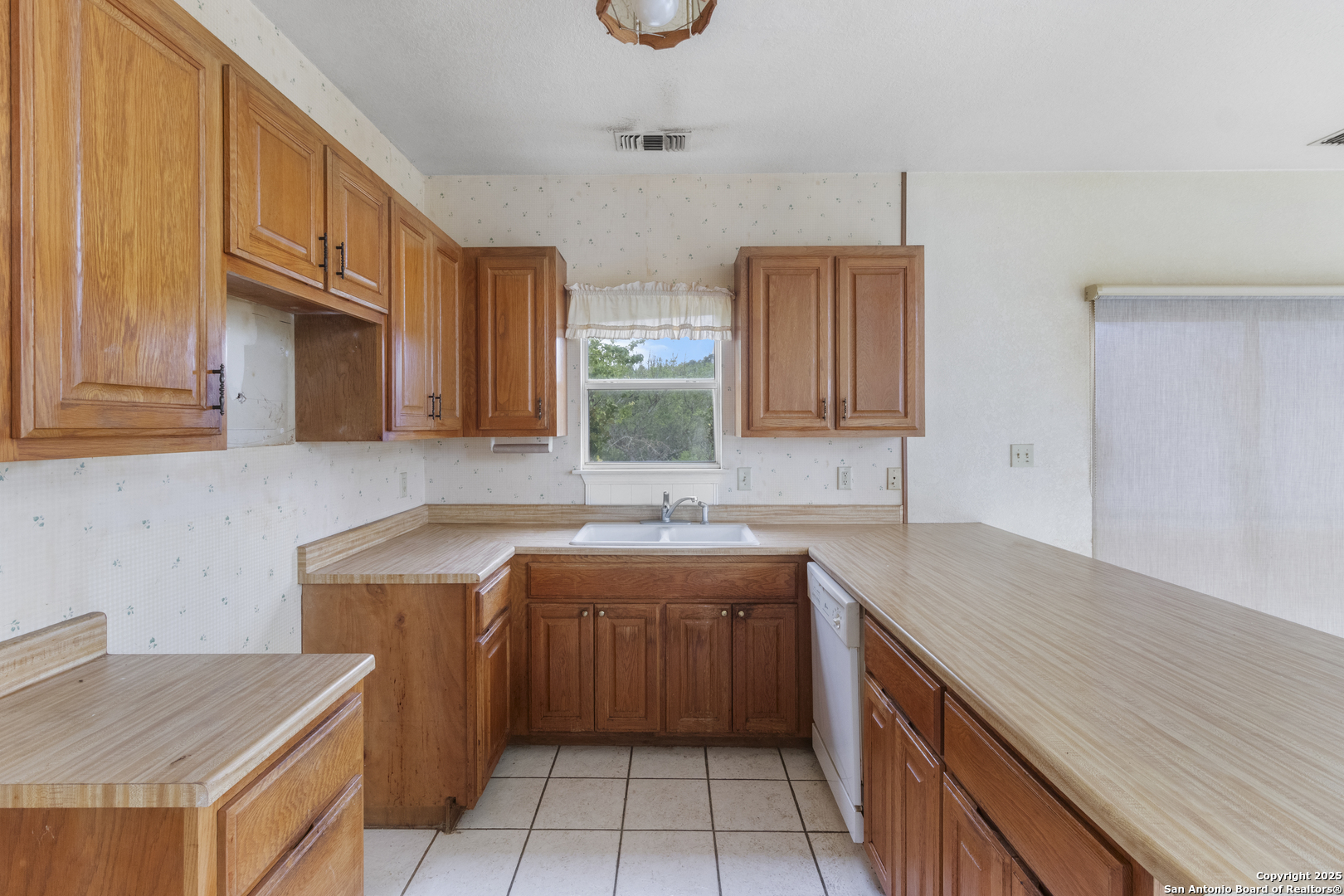 369 Deer Valley Bandera, TX 78003 - Photo 11 of 34 a kitchen with a sink dishwasher a stove and a refrigerator with wooden cabinets