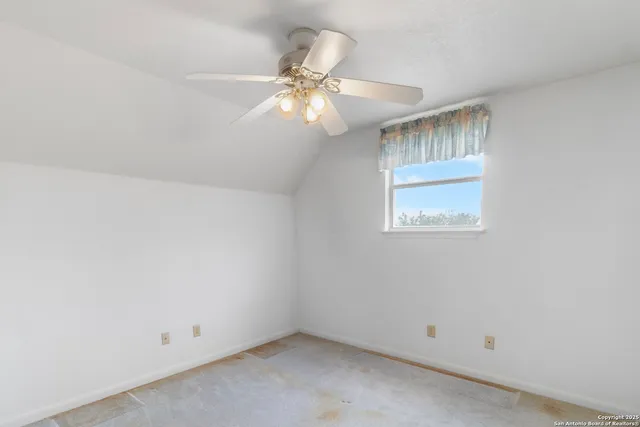 an empty room with a window and chandelier fan