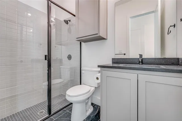 a bathroom with a granite countertop sink a toilet and shower