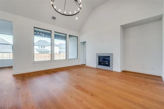 an empty room with wooden floor a fireplace and windows