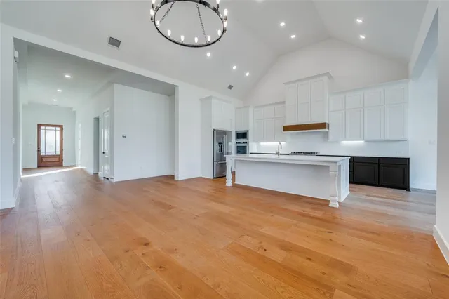 a view of kitchen and empty room with wooden floor