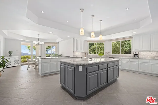 a large kitchen with kitchen island granite countertop a sink counter space appliances and cabinets