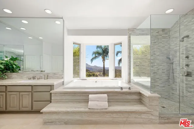 a large white bathroom with a granite countertop sink a toilet a large mirror and shower