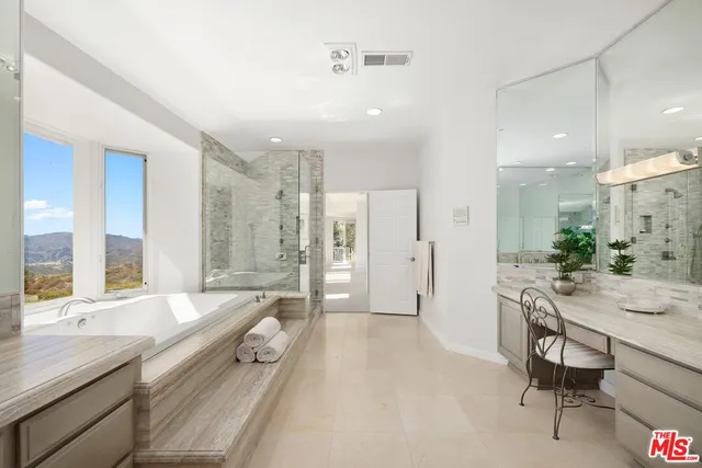 a bathroom with a granite countertop tub double vanity sink and a large mirror