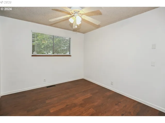 an empty room with a window and ceiling fan