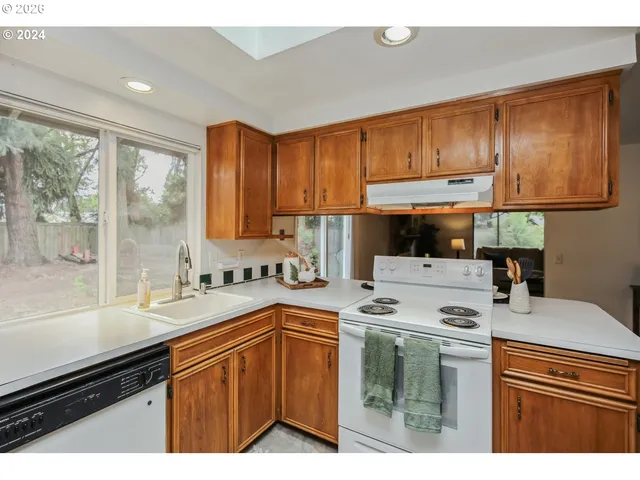 a kitchen with a sink a stove cabinets and a window