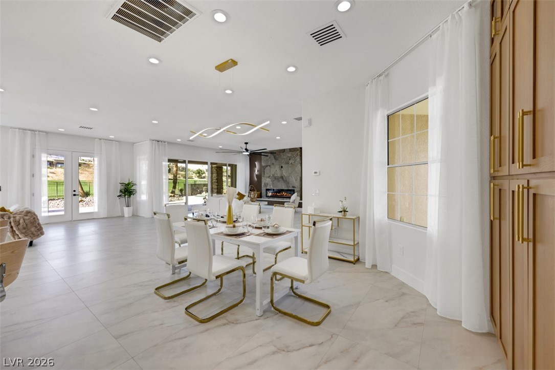 5015 Rivedro Street Las Vegas, NV 89135 - Photo 29 of 91 An open-concept living and dining area connects seamlessly to the outdoor patio through French doors, offering a spacious atmosphere.