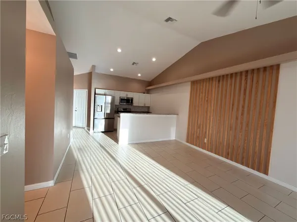 a view of an empty room with window and chandelier fan
