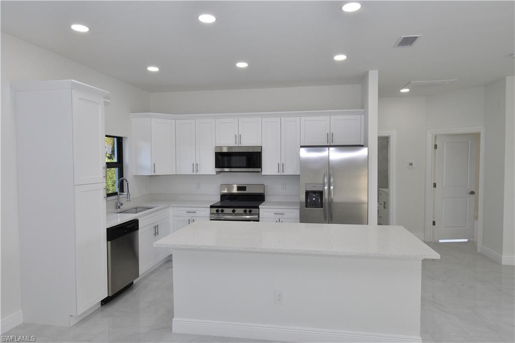 349 Naples Avenue South Lehigh Acres, FL 33974 - Photo 10 of 22 a kitchen with stainless steel appliances a refrigerator sink and microwave