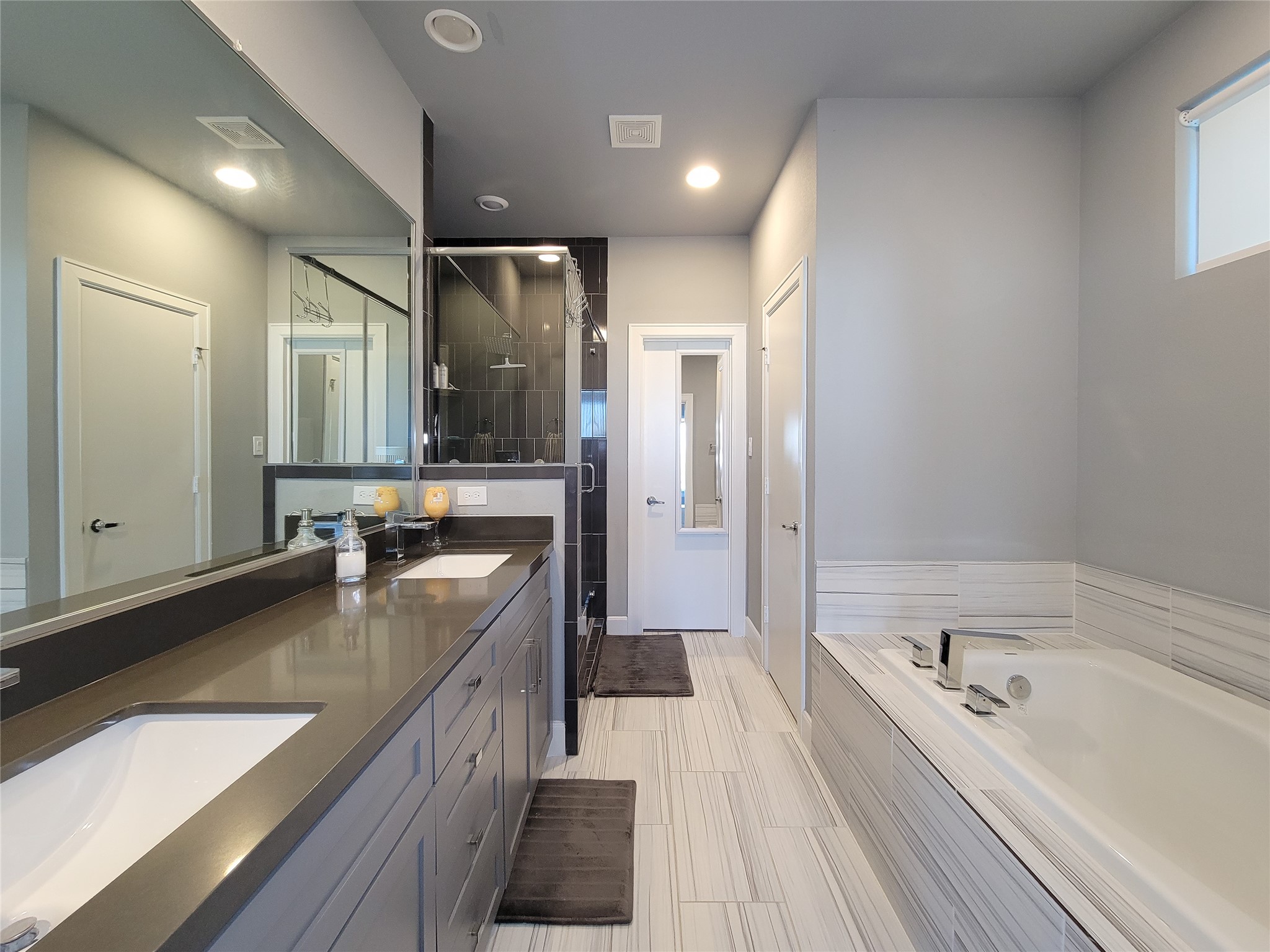 1705 Eado Point Lane Houston, TX 77003 - Photo 42 of 50 The primary bath features a dual vanity sink, a separate shower, and a luxurious soaking tub. The room is well-lit with recessed lighting and offers ample storage with contemporary cabinetry.