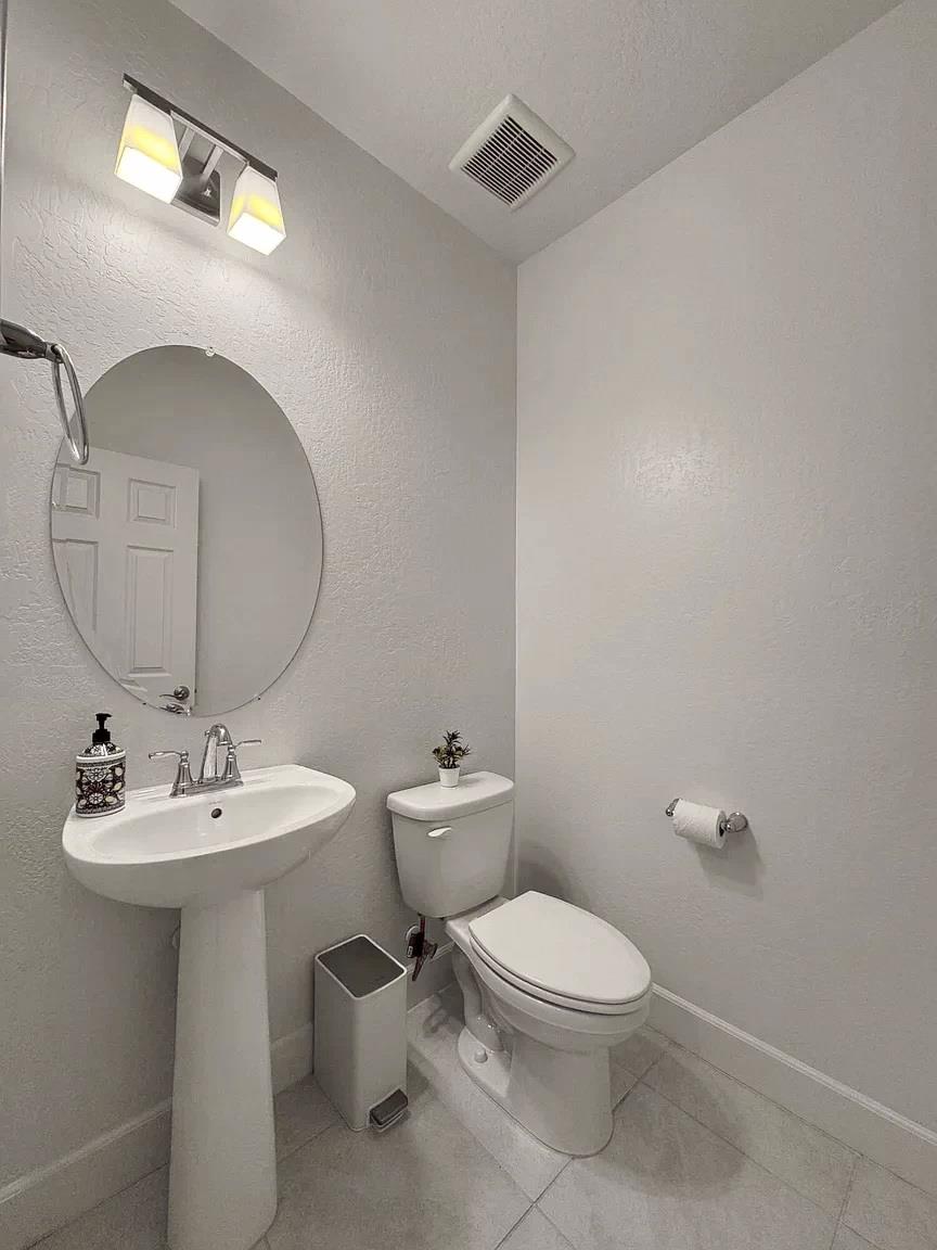 1405 West Tyler Court Visalia, CA 93291 - Photo 20 of 28 a bathroom with a toilet a sink and mirror