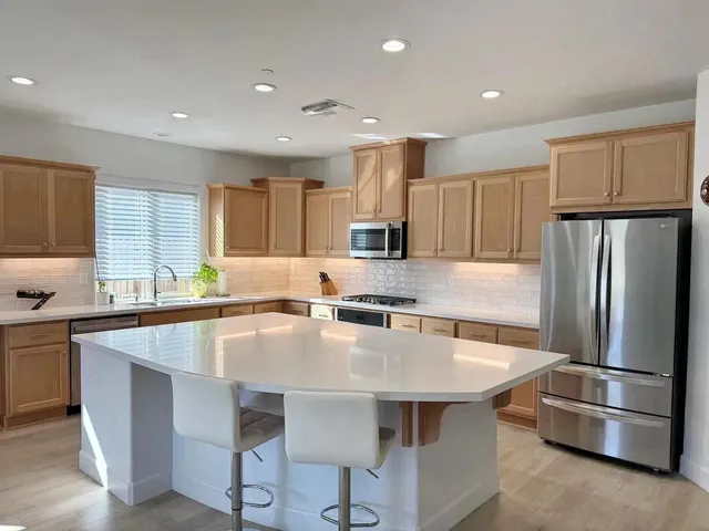 a kitchen with stainless steel appliances granite countertop a table chairs sink refrigerator and microwave