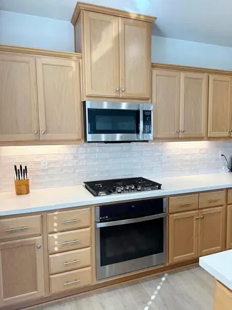 a kitchen with granite countertop white cabinets and stainless steel appliances