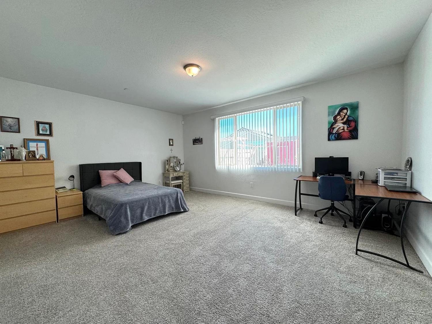 1405 West Tyler Court Visalia, CA 93291 - Photo 9 of 28 a spacious bedroom with a bed a table and a window