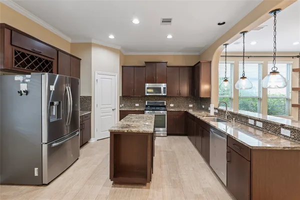a kitchen with stainless steel appliances granite countertop a refrigerator a sink a stove top oven and a refrigerator