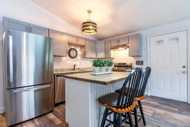 a kitchen with stainless steel appliances granite countertop a dining table chairs refrigerator and sink